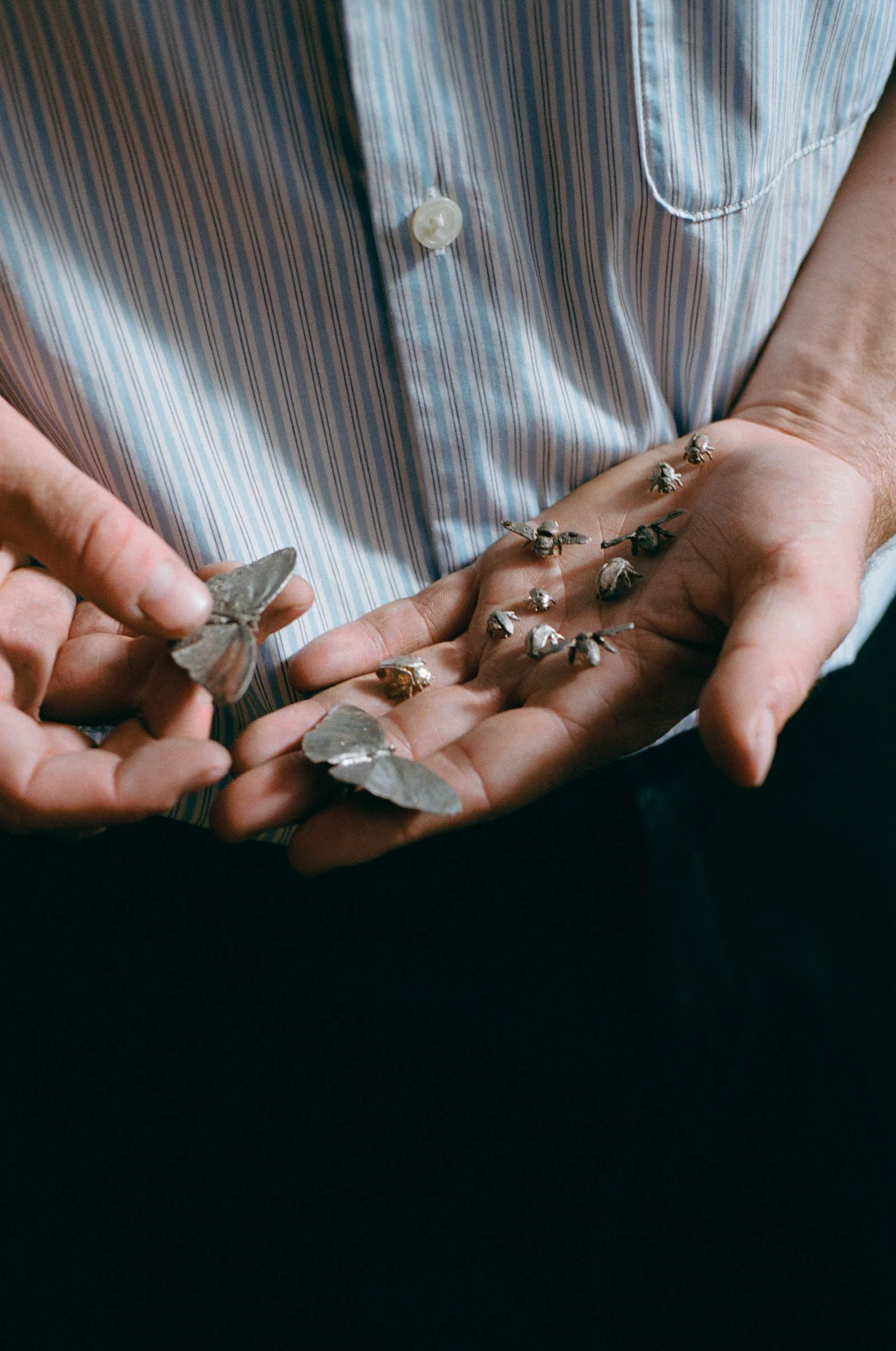 SELECTED campaign showing a person in a striped shirt holding small metal sculptures