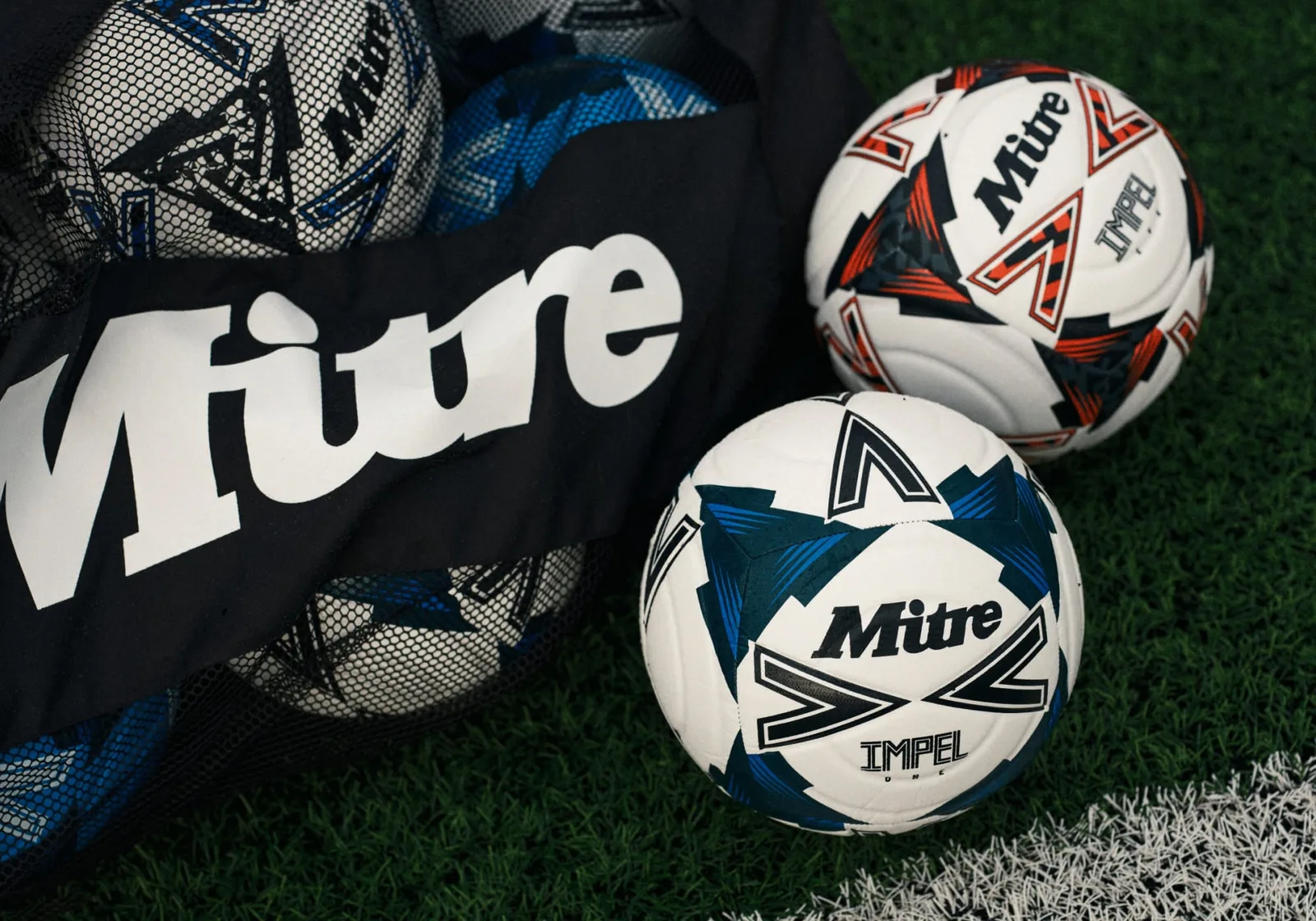 Mitre Impel footballs and a ball bag on a football pitch